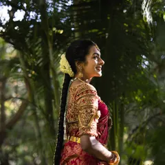 The smile of a happy bride is everything. This candid shot captures her joy, framed by the exquisite zardozi work on her red silk blouse and the traditional flowers in her hair.