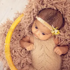 This portrait showcases an alert and curious newborn. The earthy tones of the knit outfit and the textured basket create a warm, organic setting for capturing those beautiful, wide-open eyes.