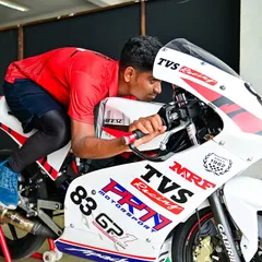 A rider getting into position on their TVS race bike. The focus and preparation before a race are intense.