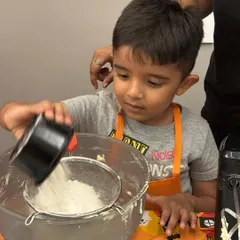 It's all about getting involved. This little chef is carefully sifting ingredients for our cupcake batter during a fun, hands-on baking session.