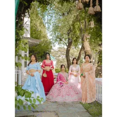 An elegant group portrait of the bride seated with her beautifully dressed bridesmaids in a garden setting.