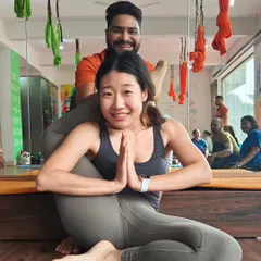 This is a "Jai Ho!" moment. With careful guidance and support, this student achieves the advanced Eka Pada Sirsasana (One-Leg-Behind-Head Pose). Her smile says everything about the joy and confidence that comes from progressing in your practice.