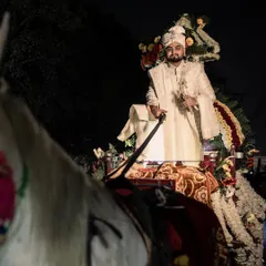 A classic shot of the groom during his baraat, seated majestically on a white horse. This image captures the regal and celebratory nature of the groom's procession, a key moment of the wedding day.