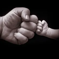 A symbolic fist bump between parent and child. This iconic shot represents the instant, powerful bond and is a client favorite for its simple yet profound message.