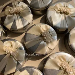 Beautifully decorated tin boxes make for wonderful return gifts. These silver tins are adorned with satin ribbons and floral embellishments, ready to be filled with sweets, candles, or other small favors.