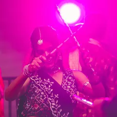 A dancer captured mid-twirl under the pink stage lights, dandiya sticks in motion. The energy on the dance floor during Navratri is truly special.