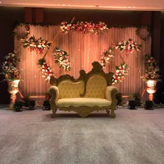 This classic stage setup combines a traditional ornate sofa with a modern geometric floral frame. It provides a distinguished setting for honoring special guests or for a formal photo session during a company anniversary celebration.