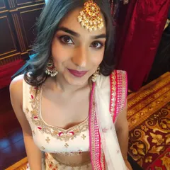 A stunning wedding guest ready for the ceremony. Her makeup features a soft brown smokey eye and a deep berry lip, paired with a traditional maang tikka for a festive touch.