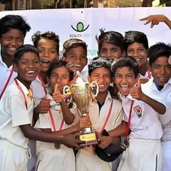 The joy of victory through our NGO partnerships. A team of young boys, supported by Reality Gives, celebrates with their trophy, showcasing the positive impact of our community sports programs.