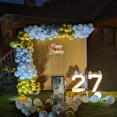 The full garden setup at dusk, with the marquee numbers and neon sign starting to glow.