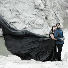A dramatic pre-wedding photo taken at a quarry, where the bride's long black gown flows majestically in the wind, creating a powerful and artistic image.