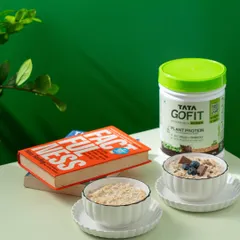 Showing the product as part of a healthy morning routine. Tata GoFit protein is presented alongside bowls of oats and a book, creating an aspirational breakfast scene.