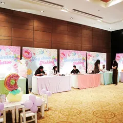 A row of activity stations set up for a Candyland party. The stations included face painting, key chain making, and other crafts to keep kids engaged.