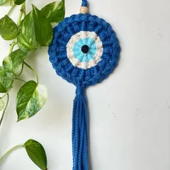This Evil Eye hanging looks beautiful against a backdrop of green leaves. It's a perfect charm to hang near a window or in your entryway.