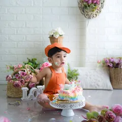 A little bit of cake, a whole lot of fun. This little guy in his cute orange overalls is getting his first taste of birthday cake, and the mess is just part of the memory.
