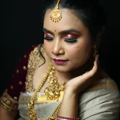 A close-up of a glamorous traditional look. The focus here is the dramatic, glittery red and black smokey eye, paired with a deep berry lip color and traditional gold jewelry.
