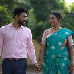 A happy couple walking hand-in-hand after their engagement pooja. The bride's makeup is soft and natural, perfect for a daytime event.