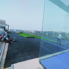 This image shows the scale of a rooftop project, with a large area covered in drainage cells before the final surface, like artificial grass, is installed.