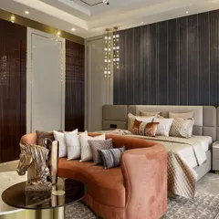This angle showcases the rich textures and layers in the master bedroom. A dark wood paneled wall with hidden doors contrasts beautifully with the soft blush sofa and the neutral, upholstered bed.