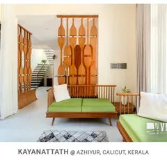 The living area at Kayanattath House features custom wooden seating and a decorative partition, with a direct view and access to the internal courtyard, blurring the line between indoors and out.