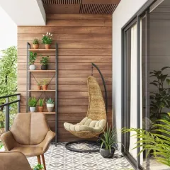 This balcony combines different seating styles with a wicker swing chair and a leather armchair for a relaxed, eclectic vibe. The wood-paneled wall and patterned floor tiles add warmth and character, while a ladder shelf provides vertical storage for plants.