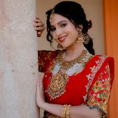 A close-up that highlights the bride's happy expression and the intricate, heavy gold jewelry that is characteristic of a South Indian wedding.