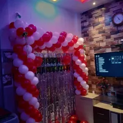 Even a small space at home can be transformed for a special anniversary. Here, I created a red and white balloon arch over the entertainment unit, using a silver shimmery curtain as a backdrop to add a touch of glamour.