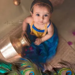 A beautiful baby girl styled as Radha, surrounded by peacock feathers and traditional elements. I use vibrant colors and authentic props to create a rich, story-filled portrait.