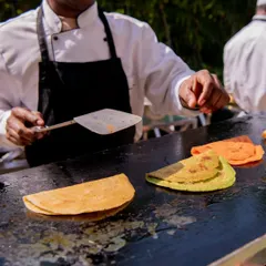 A chef in action, expertly preparing colorful moong dal chillas on a hot griddle. This live cooking element adds a dynamic and engaging touch to the event.