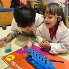 A moment of discovery between two budding scientists. Collaborative experiments like this teach teamwork and problem-solving as they watch their creation come to life in a test tube.