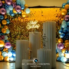 A detailed look at the stylish birthday setup, showing the textured pedestals and birdcage details that add a unique touch to the shimmering gold backdrop.