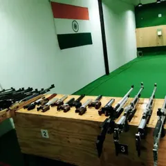 A view of the shooting lanes from behind our collection of air rifles. The green flooring and wood paneling create a professional and focused atmosphere.