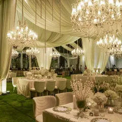Beneath a flowing canopy of ivory fabric and a sky of glittering chandeliers, we set the stage for an evening of pure elegance. This all-white and gold theme creates a timeless and luxurious dining experience for guests.
