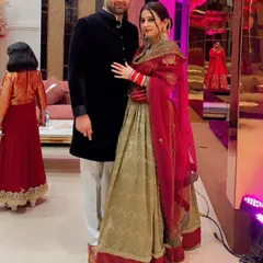A picture-perfect moment. Our bride looks stunning in her custom-designed lehenga, featuring a beautiful blend of olive green and a rich red embroidered dupatta.