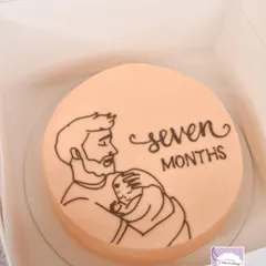 A bento-style cake for a seven-month milestone, featuring a simple line drawing of a father and baby.