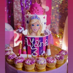 Bring the glamour to your party with a custom Barbie-themed cake. This two-tiered creation features a portrait of Barbie, a fondant crown, and matching cupcakes, perfect for a fan's birthday.