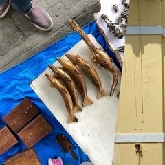 A collage of street finds. Carved wooden fish and tiny drums from a market stall are paired with the simple, yellow facade of a building, creating a playful composition.