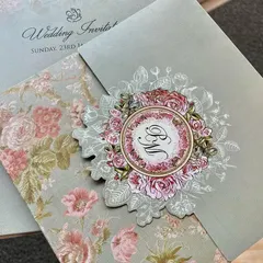 A lovely invitation featuring a die-cut floral monogram. The soft green and pink color palette is modern and refreshing.