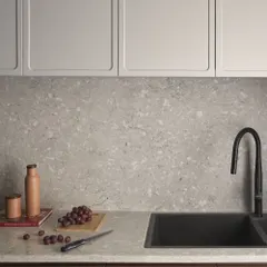 A detail of the kitchen sink area, where natural elements like grapes and a wooden board complement the terrazzo countertop. It's a space designed for real life.