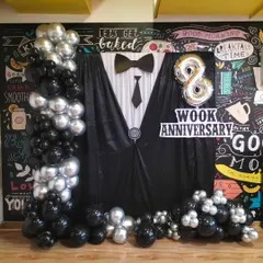 A creative tuxedo-themed backdrop for a work anniversary celebration. We design custom setups with balloon columns and foil numbers to make your internal office milestones memorable.