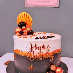 A modern chocolate truffle cake for a 23rd birthday. The design features a two-tone effect in grey and white, accented with black, gold, and copper spheres for a contemporary and masculine feel.
