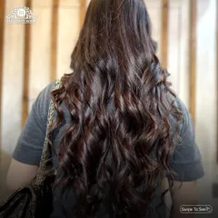 Showcasing voluminous, bouncy curls on long, dark hair. A professional blow-dry and curl service like this can completely transform your look for a day or night out.