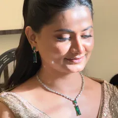 A close-up of the elegant engagement makeup. The focus is on a flawless, dewy skin finish and soft, shimmering eyeshadow that complements her emerald and diamond jewelry.