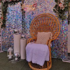 Another look at the versatile sequin wall setup. Here it's styled with a "Bunny Bash" neon sign, disco balls, and a plush-covered peacock chair.
