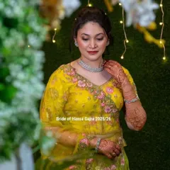 A full portrait of a bride wearing colored mehendi. The design on her hands and arms perfectly matches the floral embroidery on her yellow lehenga, creating a cohesive and stunning look.
