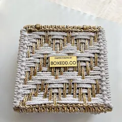 This intricate white and gold woven box showcases our commitment to unique packaging. The custom metal plaque with our branding is a mark of quality and thoughtful curation.
