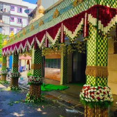 Here is a wide view of a wedding house entrance. I created a large *chappara* with checkered-pattern woven leaves and pillars decorated with sugarcane and fresh flowers.