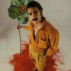 From the 'Flower Power' editorial, this look features a retro-inspired mustard corduroy shirt and trousers. The oversized, handmade flower prop adds a surreal and artistic element to the shoot.