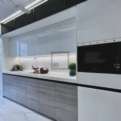 This angle shows the full-height unit with an integrated microwave, a great way to save counter space. The reflective white upper cabinets make the entire kitchen feel brighter and more open.