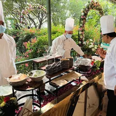 An outdoor live station at a day wedding, where our chefs prepare food amidst a beautiful garden setting. This setup shows our ability to adapt our luxury catering services to any destination or venue.